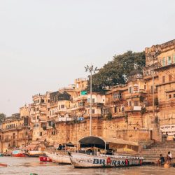 Picturesque view of Varanasi ghats along the Ganges River with bustling boats and ancient architecture.